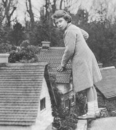 an old black and white photo of a woman standing on top of a house