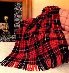 a purple and black plaid blanket sitting on top of a couch next to a fireplace