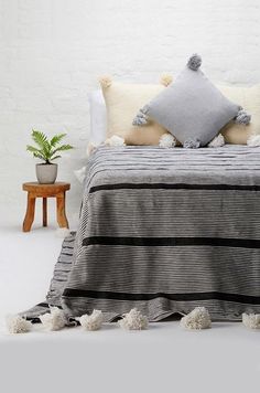 a bed with black and white striped bedspread, pom poms on the bottom