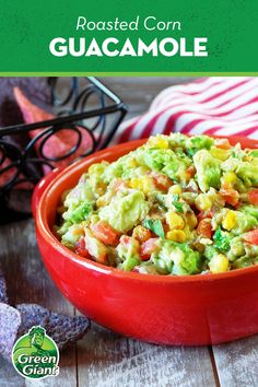 a red bowl filled with guacamole on top of a wooden table