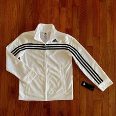 Adidas Full-Zip White Boys Tricot Jacket With Stripes That Run Down Sleeve. Welt Pockets, Rib Sleeve Cuff And Rib Hem. Embroidered Adidas Brand Mark On Wearer's Left Chest. Condition: Brand New With Tags. Size: Boys Medium (10/12) Material: 100% Polyester, Zipper Closure. Machine Wash White Adidas Track Jacket For Winter, Adidas White Track Jacket For Winter, Adidas White Winter Track Jacket, White Track Jacket With Zipper For Spring, White Track Jacket For Spring, White Track Jacket With Zipper Closure For Fall, White Spring Track Jacket With Zipper, Cotton Outerwear With Three Stripes For Fall, Adidas White Track Jacket For Fall