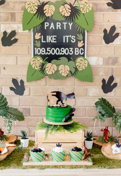 a party table with cake, cupcakes and decorations