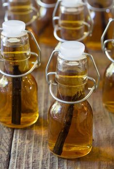 several glass jars filled with different types of oil and cinnamon sticks in them on top of a wooden table