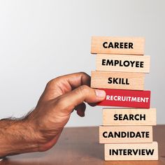 a person stacking wooden blocks with the words career, employee, skill, employment and search candidate written on them