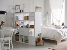 a bedroom with white walls and furniture in it, including a bed that is next to a desk