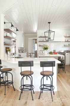 three stools sit at the center of a kitchen island