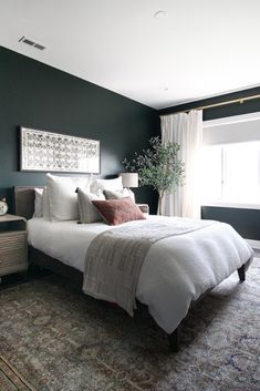 a bedroom with green walls, white bedding and a large rug on the floor