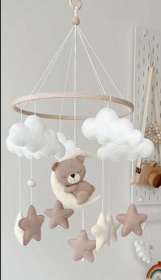 a teddy bear is sitting on the moon and stars mobile hanging from a ceiling in a child's room