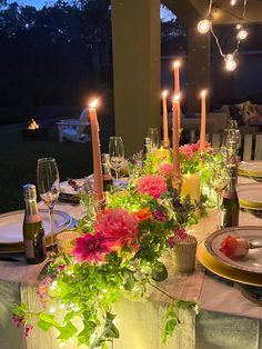 the table is set with flowers and candles on it for an outdoor dinner or party