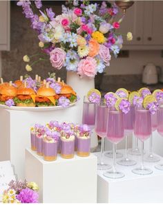 a table topped with lots of glasses filled with purple liquid and food on top of it