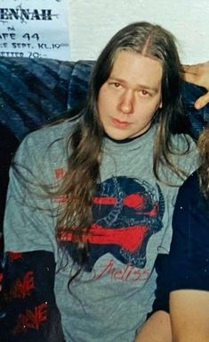 a man with long hair sitting next to a woman in a gray t - shirt