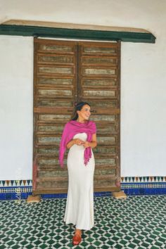 a woman standing in front of a door with a pink shawl on her head