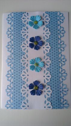 some blue flowers are sitting on top of a white doily with polka dot paper