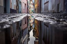 a narrow alleyway with buildings reflected in the water