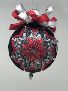 a red and black ornament hanging from a string with a bow on it