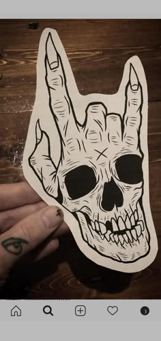 a person holding up a sticker with a skull in the shape of a hand