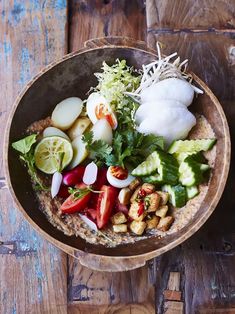 a wooden bowl filled with lots of different types of food on top of a table