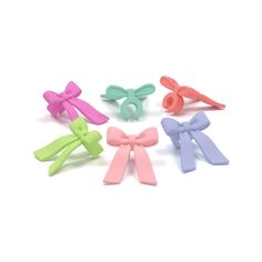 four different colored bows are shown in the shape of hair clips on a white background