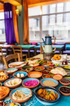 a table topped with lots of different types of food on top of blue cloth covered tables