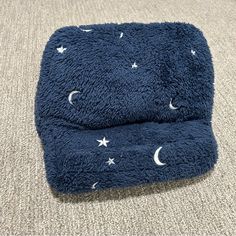 a blue dog bed with stars and moon print on the side, sitting on carpet