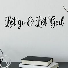 let go and let god wall decal on the wall next to a stack of books