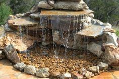 an outdoor fountain with rocks and water running down it