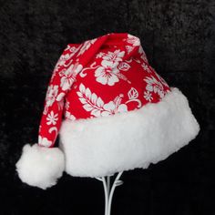 "If you have a tropical Santa in your home he or she may need a hat. This novelty Santa hat is made up in a Christmas red and white Hawaiian traditional hibiscus print cotton fabric. Hat is decorated with a snowy white faux Sherpa fur fabric trim. Put Santa in a tropical island mode for that balmy warm holiday season. The sizing on the hat is generous and will fit most adult head sizes. The styling is a slouch cone, traditional Santa look. There is a snowy white pompom stitched on the top. Openi Adjustable Red Hats For Holiday, Adjustable Red Hat For Holiday, Red Mini Cap For Beach, Red Adjustable Christmas Hat, Adjustable Red Christmas Hat, White Christmas Hat As Gift, White Christmas Holiday Hat, Festive Red Adjustable Hat, Red Adjustable Festive Hat