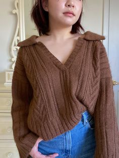 a woman wearing a brown sweater and jeans