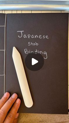 a hand holding a large white object in front of a sign that says japanese stab binding