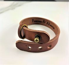 two leather bracelets with brass buttons on them