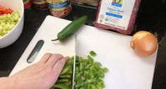 a person cutting up vegetables on a cutting board