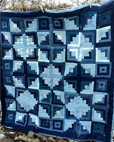 a blue and white quilt hanging from a clothes line