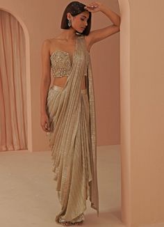 Glam Vibes in this gold gleam pleated drape saree teamed with a corset encrusted with stone work and zardosi in gold hues. This ensemble is a ready to wear saree for your ease ! Blouse can have straps added for ease. Composition: Saree - Lycra Net, Blouse- Net , Lining-Butter Crepe All products can be customised for sleeves, length of blouse and neck design Delivery : 4-6 weeks as the product is hand crafted. Check Size Guide or choose MySize for free customisation (All Sizes above XL can be made at 15% additional cost) For more information and sizes please contact fabiliciousfashion@gmail.com or visit our Copenhagen studio. About the Designer : Parul Gandhi is a name that exudes opulence and elegance. The design philosophy of Parul Gandhi Label revolves around color balance and placement Festive Gold Embellished Pre-draped Saree, Fitted Gold Pre-draped Saree For Festive Occasions, Gold Pre-draped Saree With Cutdana For Party, Gold Embellished Blouse Piece With Traditional Drape, Gold Embellished Saree With Traditional Drape, Gold Embellished Traditional Drape Blouse Piece, Gold Embellished Saree For Reception, Glamorous Gold Blouse Piece For Designer Wear, Glamorous Gold Floor-length Choli