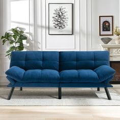 a blue couch sitting in a living room next to a fireplace and potted plant