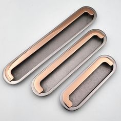 three shiny metal handles on a white surface