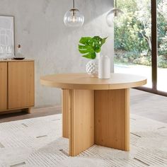 a round wooden table sitting on top of a white rug