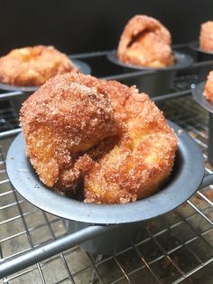 sugar covered doughnuts sitting in muffin tins on a cooling rack, ready to be eaten