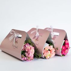 three pink boxes with flowers in them on a white surface