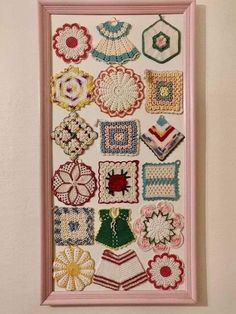 a pink frame with many different crocheted items hanging on it's wall