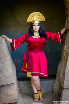 a woman in a red dress and gold headdress poses for a photo with her hands on her hips