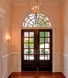 an entryway with two doors and a chandelier