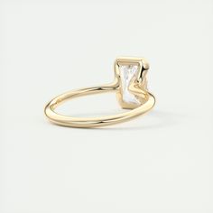 a yellow gold ring with a square shaped white diamond in the center and a thin band around it