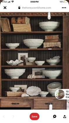 a wooden bookcase filled with lots of bowls and other items on top of it