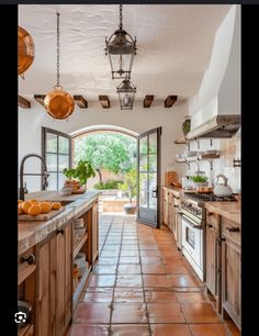 an open kitchen with wooden cabinets and tile flooring, along with hanging pots and pans on the wall