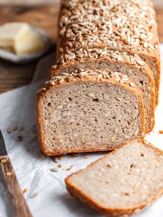 sliced loaf of bread sitting on top of a piece of paper next to a knife