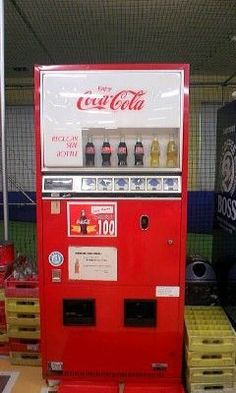 a coca - cola machine sitting on top of pallets in a room filled with boxes