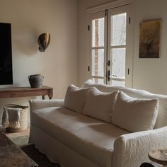 a white couch sitting in front of a flat screen tv