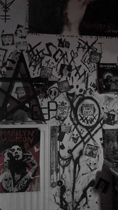 black and white photograph of graffiti on the wall with various stickers all over it