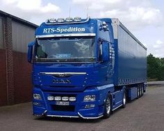 a blue semi truck parked in front of a building