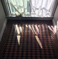 the shadow of two arrows is cast on the floor in front of a window